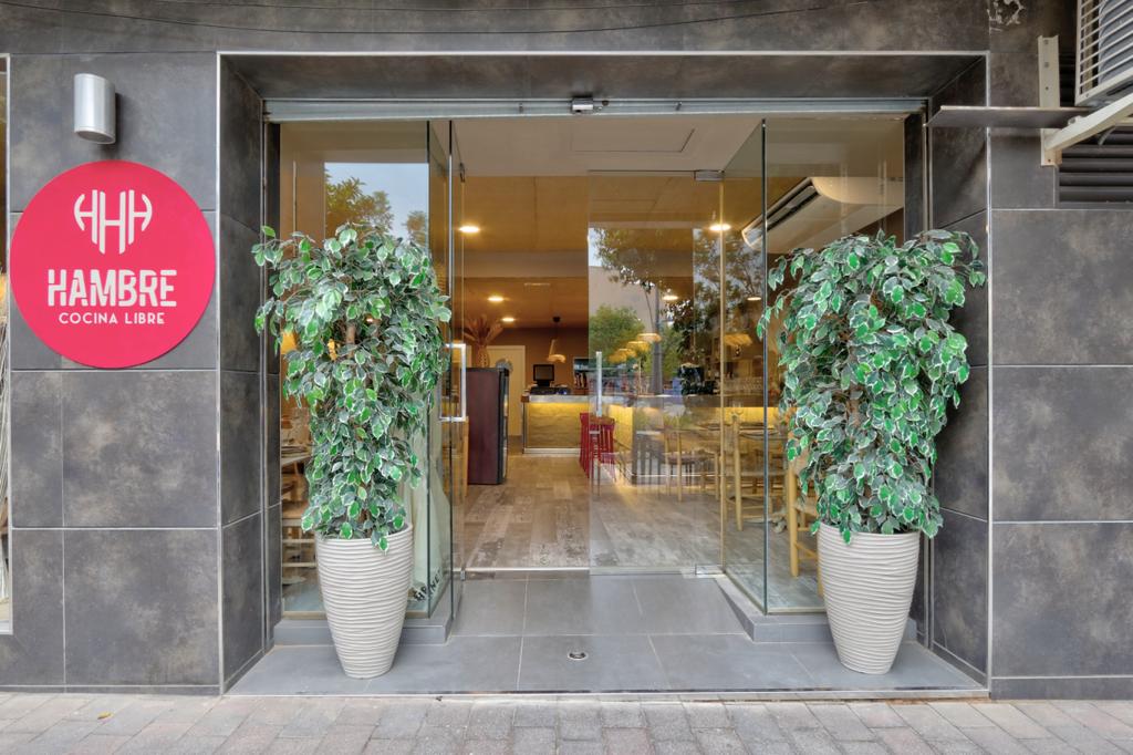 Entrada del restaurante Hambre, cocina libre, con el logo rosa en la pared